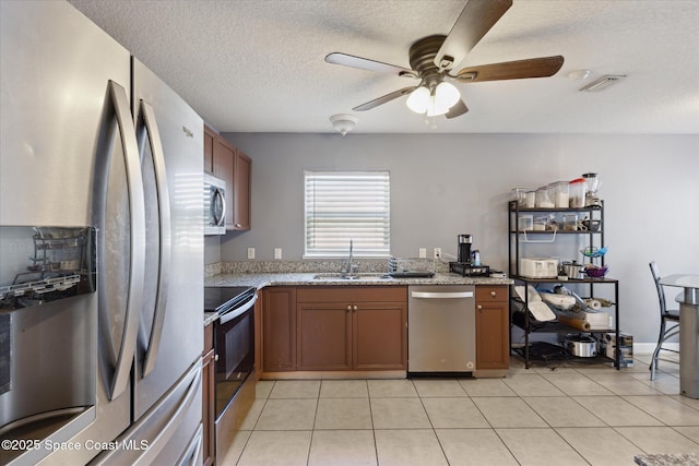 kitchen with ceiling fan, sink, stainless steel appliances, a textured ceiling, and light tile patterned flooring