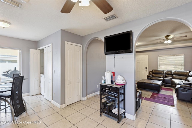 tiled living room featuring a textured ceiling and ceiling fan