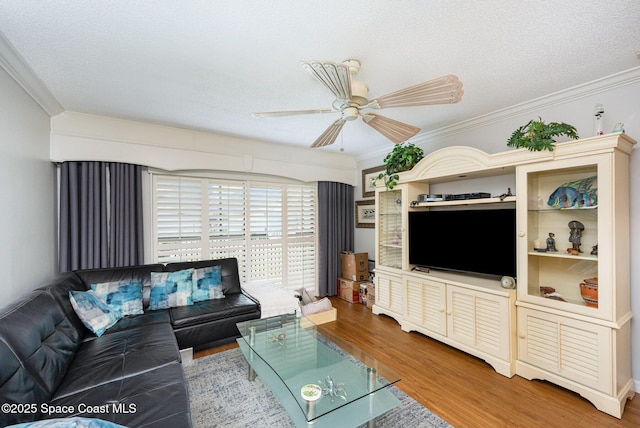 living room with a textured ceiling, ceiling fan, ornamental molding, and wood-type flooring