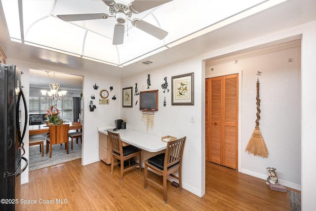 dining room with ceiling fan with notable chandelier and hardwood / wood-style flooring