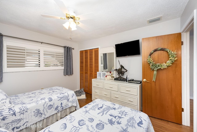 bedroom featuring light hardwood / wood-style floors, a closet, ceiling fan, and a textured ceiling