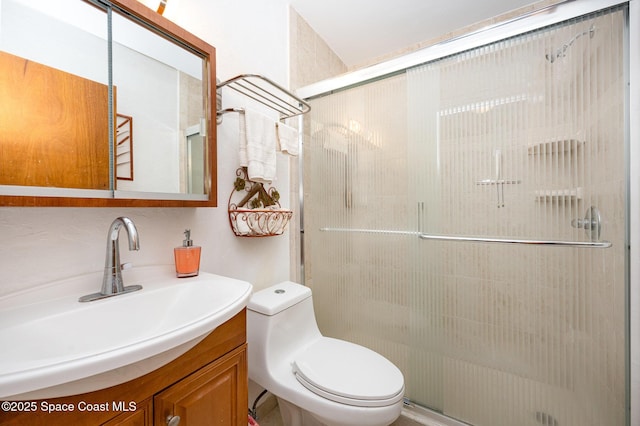 bathroom with toilet, a shower with shower door, and vanity