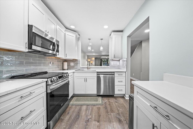 kitchen with hanging light fixtures, white cabinets, stainless steel appliances, and sink