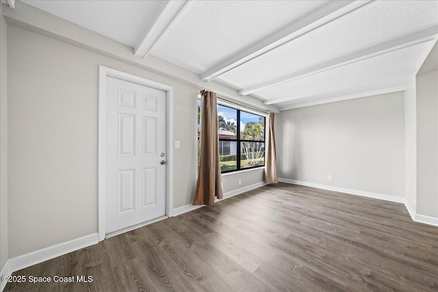 foyer entrance with beam ceiling, dark hardwood / wood-style flooring, and a textured ceiling