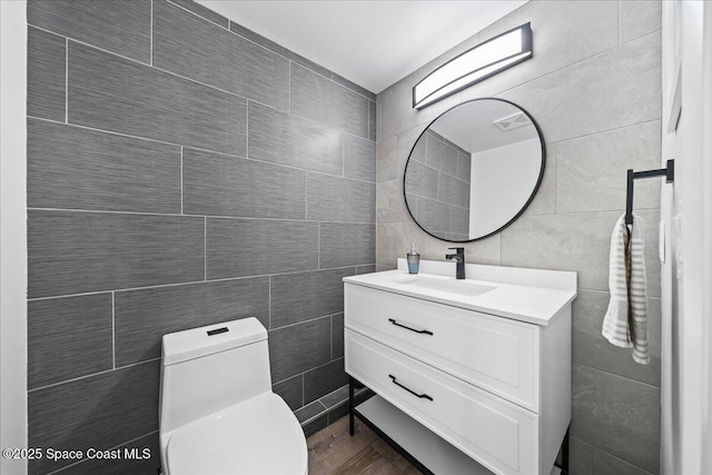 bathroom with vanity, toilet, and tile walls