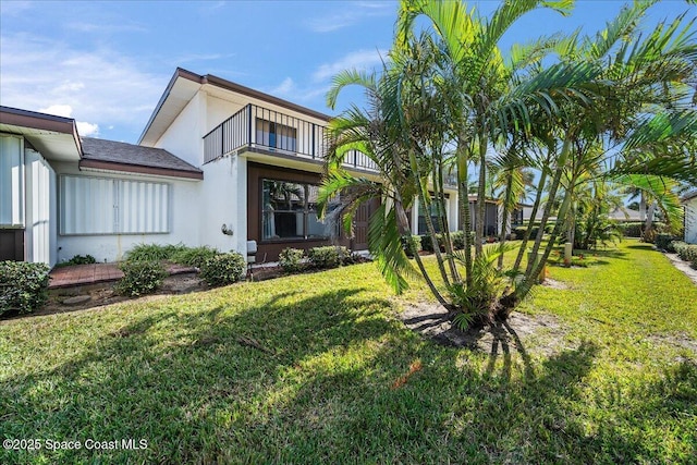 view of front of home featuring a balcony and a front lawn