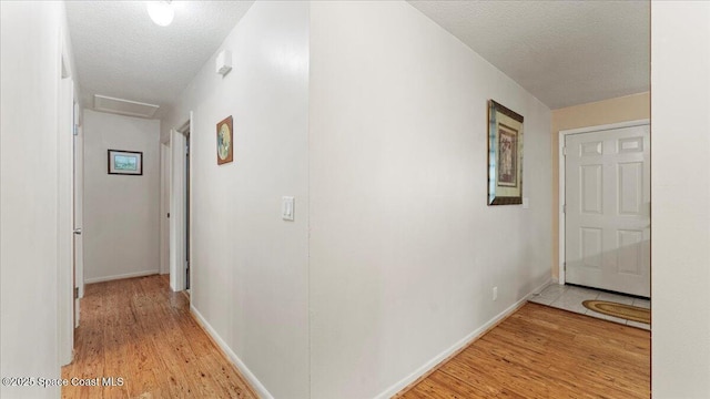 hall with a textured ceiling and light hardwood / wood-style flooring