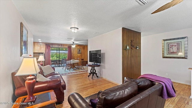 living room with ceiling fan, light hardwood / wood-style flooring, and a textured ceiling