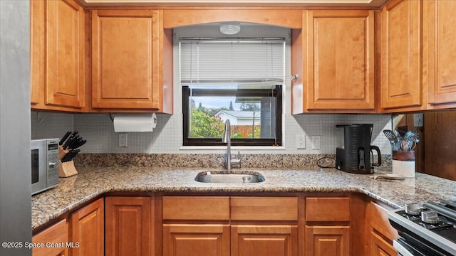 kitchen featuring sink, light stone counters, stove, and decorative backsplash