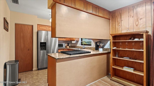 kitchen featuring kitchen peninsula, sink, light stone countertops, and appliances with stainless steel finishes