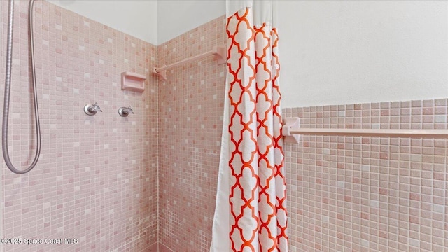 bathroom with curtained shower and tile walls