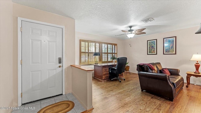 office with light wood-type flooring, a textured ceiling, and ceiling fan