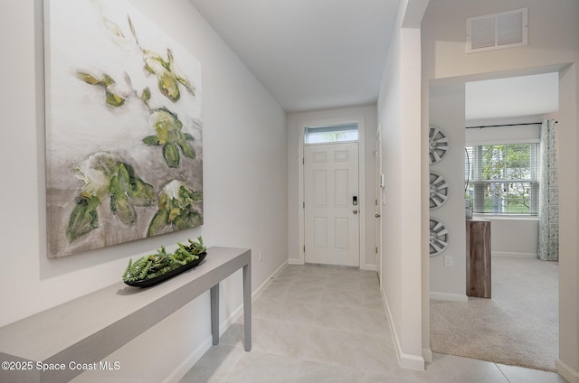 foyer featuring light tile patterned flooring, light colored carpet, visible vents, and baseboards