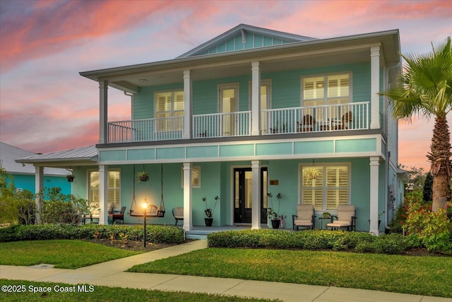 view of front of home with a balcony and a lawn