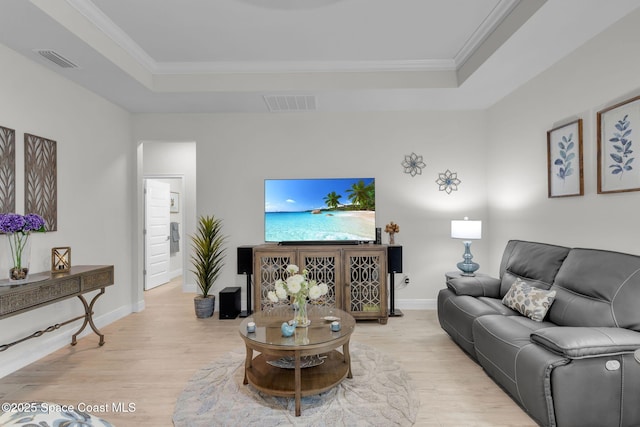 living room with light hardwood / wood-style floors, a raised ceiling, and crown molding