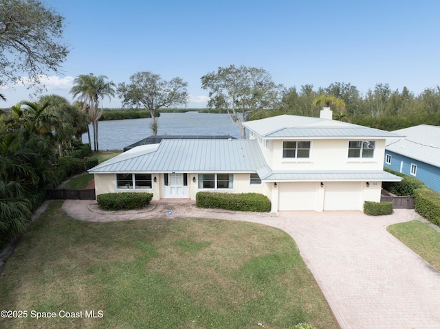 view of front of property featuring a garage, a front yard, and a water view