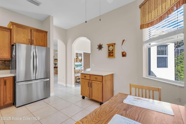 kitchen featuring light tile patterned floors, stainless steel refrigerator, and tasteful backsplash