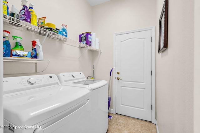 clothes washing area featuring washer and clothes dryer and light tile patterned floors