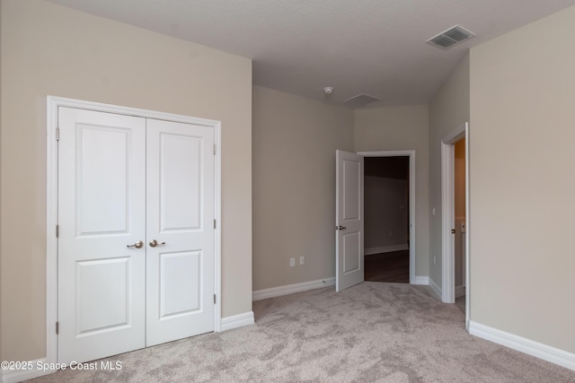 unfurnished bedroom with light carpet and a closet