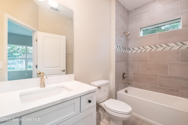 full bathroom featuring vanity, tiled shower / bath combo, and toilet