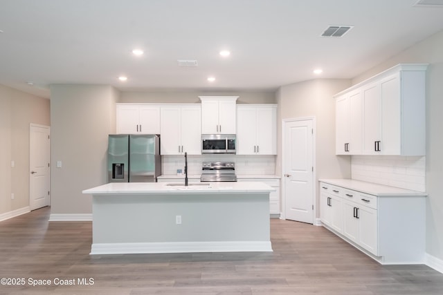 kitchen featuring backsplash, white cabinetry, an island with sink, and appliances with stainless steel finishes