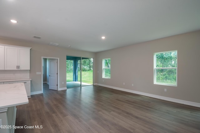 unfurnished living room featuring dark hardwood / wood-style floors and a healthy amount of sunlight