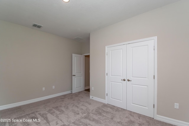 unfurnished bedroom with light carpet and a closet