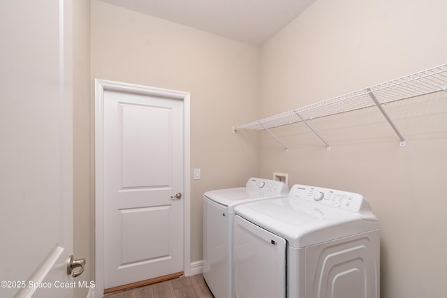 laundry room with washing machine and clothes dryer and light wood-type flooring