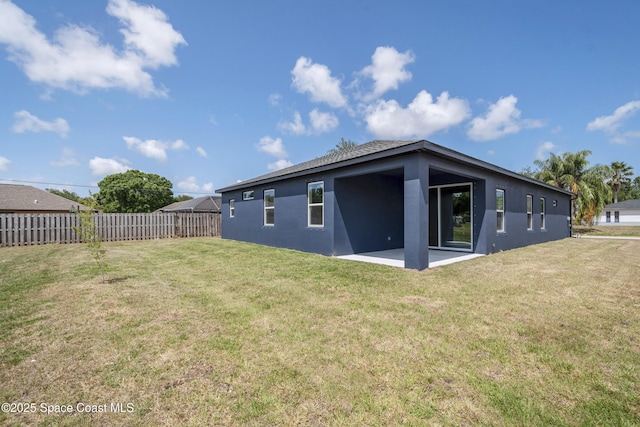 228 Dunlap Ave SE, Palm Bay, FL 32909 - rear view of property featuring fence, stucco siding, a lawn, and a patio area