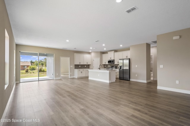 228 Dunlap Ave SE, Palm Bay, FL 32909 - unfurnished living room featuring visible vents, wood finished floors, a sink, baseboards, and recessed lighting