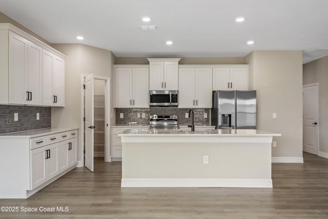 228 Dunlap Ave SE, Palm Bay, FL 32909 - kitchen featuring white cabinets, appliances with stainless steel finishes, a kitchen island with sink, light countertops, and tasteful backsplash