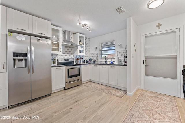 kitchen with sink, stainless steel appliances, wall chimney range hood, a textured ceiling, and white cabinets