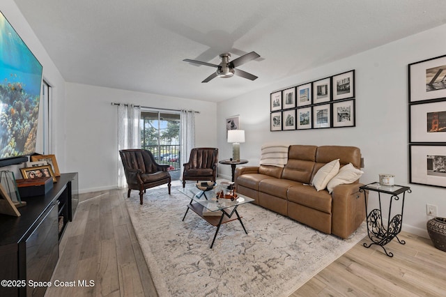 living room featuring ceiling fan, light hardwood / wood-style floors, and a textured ceiling