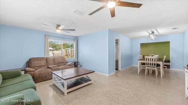 living room featuring ceiling fan and a textured ceiling