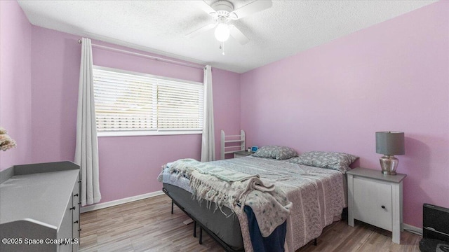 bedroom with a textured ceiling, light hardwood / wood-style floors, and ceiling fan