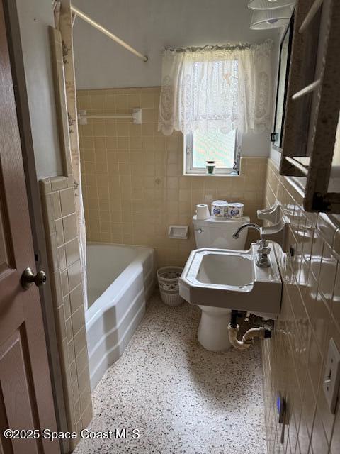 bathroom featuring shower / tub combo with curtain, tile walls, and sink