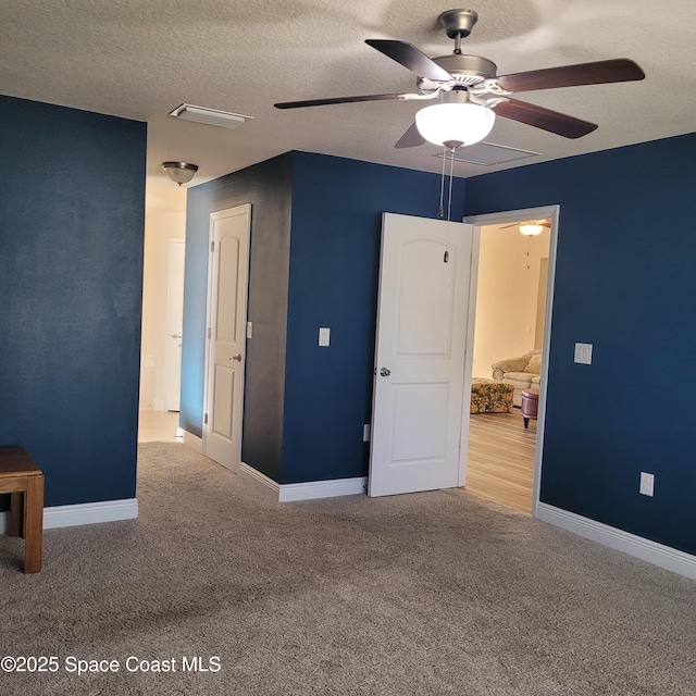 unfurnished bedroom with ceiling fan, carpet, and a textured ceiling