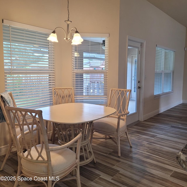 dining space featuring lofted ceiling, dark hardwood / wood-style floors, and a notable chandelier