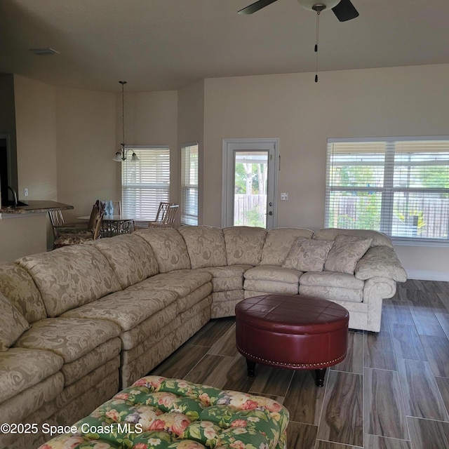 living room featuring ceiling fan with notable chandelier and dark wood-type flooring