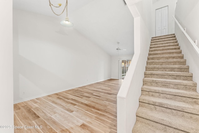 stairway with wood-type flooring, vaulted ceiling, and ceiling fan