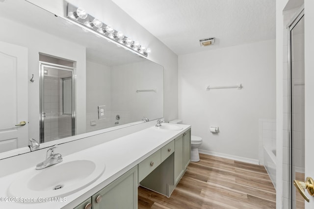 full bathroom featuring toilet, shower with separate bathtub, a textured ceiling, vanity, and hardwood / wood-style flooring