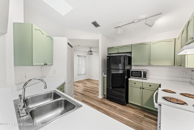 kitchen featuring black fridge, sink, and green cabinetry