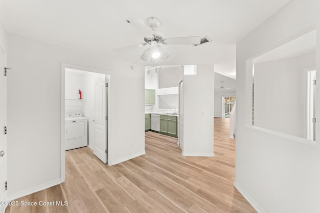 interior space with ceiling fan, washer / clothes dryer, sink, and light wood-type flooring