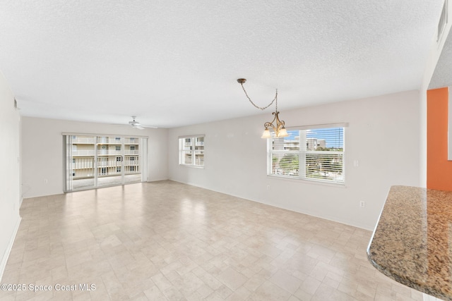 interior space featuring a textured ceiling and ceiling fan with notable chandelier