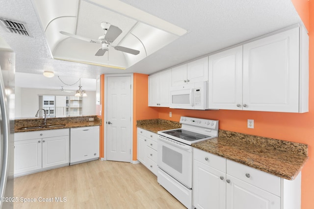 kitchen with white cabinetry, sink, white appliances, and dark stone countertops