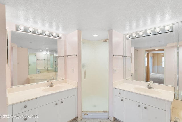 bathroom featuring tile patterned flooring, a textured ceiling, walk in shower, and vanity