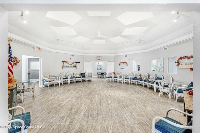 workout area featuring ceiling fan, crown molding, a tray ceiling, and hardwood / wood-style flooring