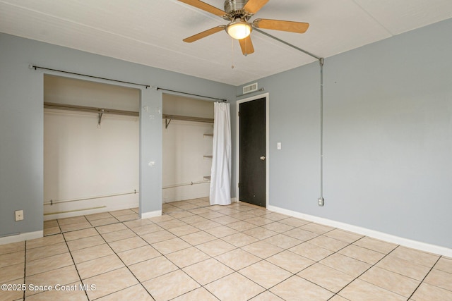 unfurnished bedroom featuring ceiling fan, multiple closets, and light tile patterned floors