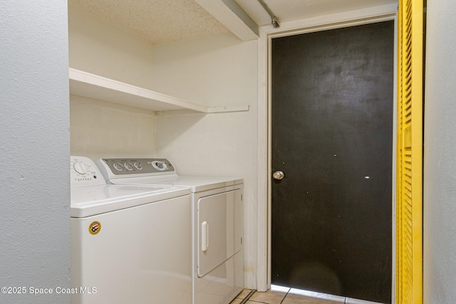 laundry room with a textured ceiling, light tile patterned floors, and independent washer and dryer