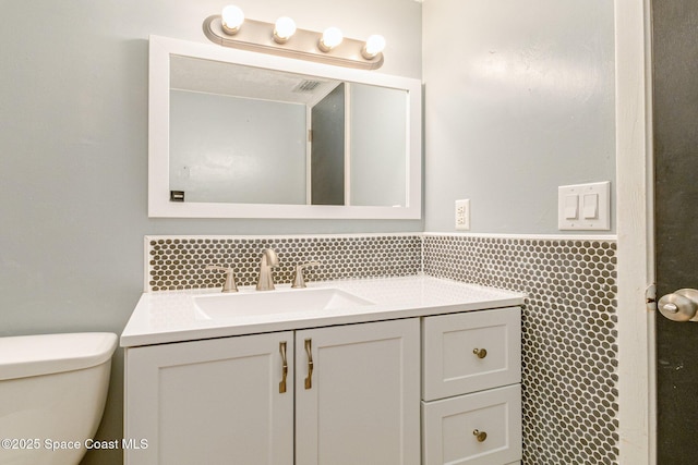 bathroom with toilet, backsplash, and vanity